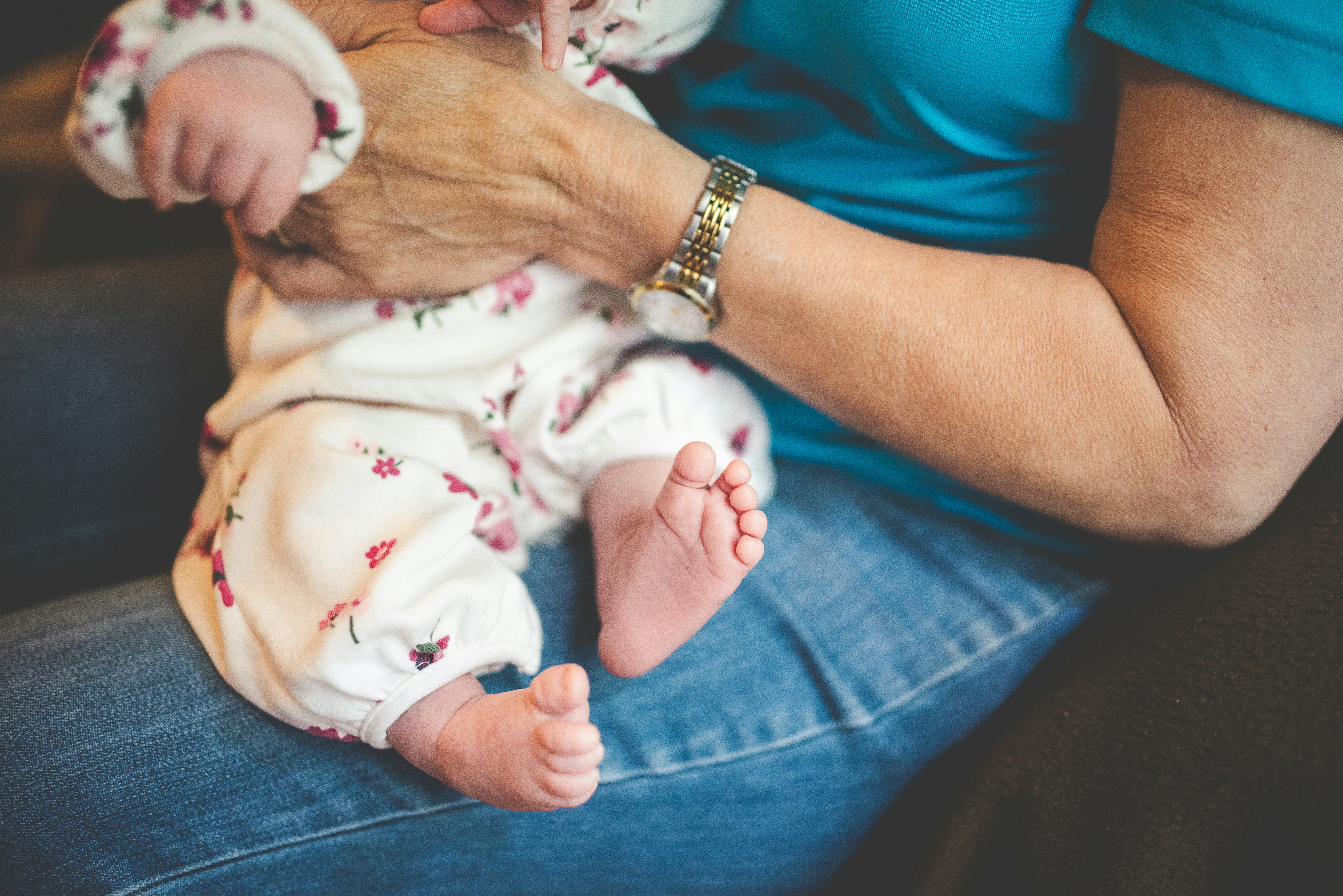 person in blue denim jeans carrying baby in white onesie